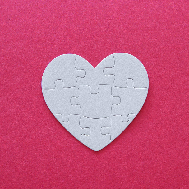 Top view image of paper white heart puzzle over pink background. Health care, donate, world heart day and world health day concept - Fotoğraf, Görsel