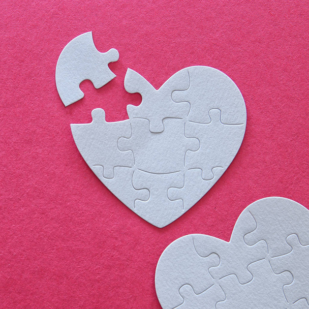 Top view image of paper white heart puzzle with missing piece over pink background. Health care, donate, world heart day and world health day concept - Fotografie, Obrázek