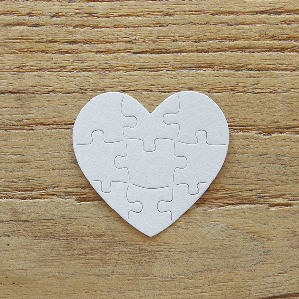 Top view image of paper white heart puzzle over wooden table. Health care, donate, world heart day and world health day concept - Fotó, kép