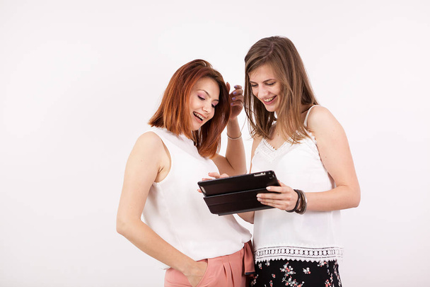 Two girl friends smiling and looking at a tablet PC - Fotografie, Obrázek