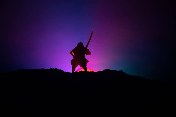 Myśliwiec z sylwetka miecz ninja niebo. Samuraj na szczycie góry z ciemnym stonowanych mglisty tło. Selektywny fokus - Zdjęcie, obraz