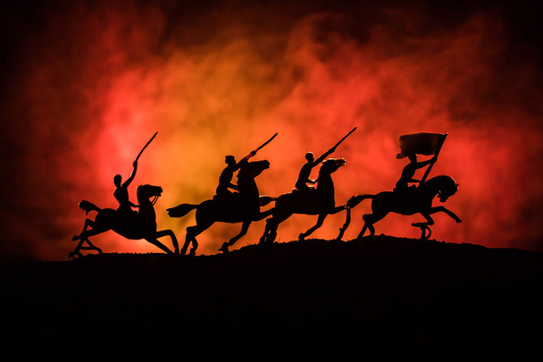 Офицер Мировой Войны (или воин) всадник на коне с мечом, готовым к бою, и солдаты на темном туманном фоне. Поле битвы боевых солдат. Селективный фокус
 - Фото, изображение