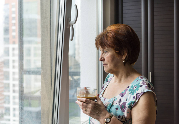 adult woman with a Cup of coffee near the window in the room - Foto, immagini