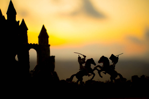 Scena di battaglia medievale con cavalleria e fanteria. Silhouette di figure come oggetti separati, lotta tra guerrieri sullo sfondo del tramonto con vecchio castello gotico. Focus selettivo
 - Foto, immagini