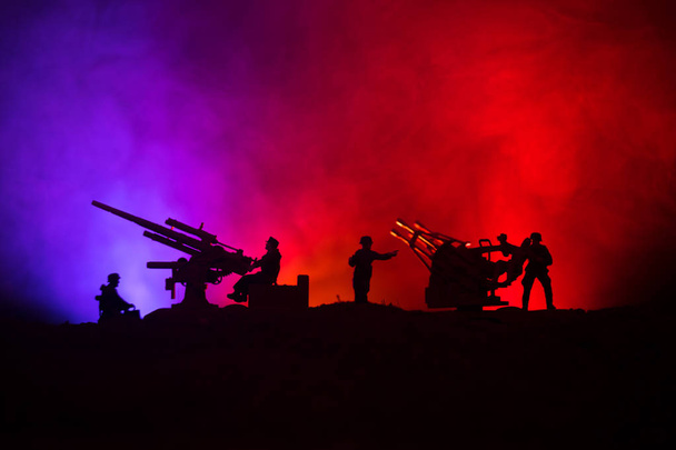 Un canon anti-aérien et des silhouettes militaires combattant sur fond de brouillard de guerre, des silhouettes de soldats de la guerre mondiale sous un ciel nuageux la nuit
 - Photo, image