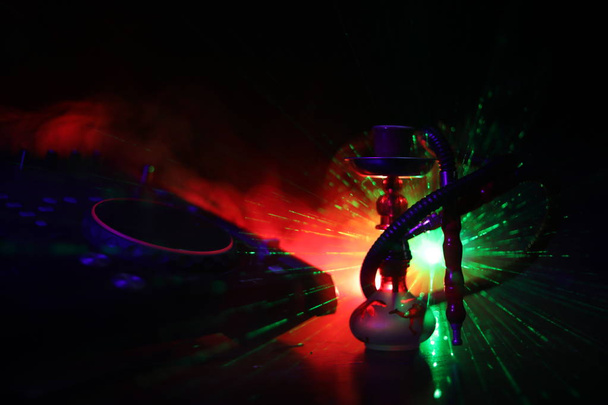 Concepto de club de fiesta de Shisha. Mezclador de DJ con fondo de discoteca oscura con elegante shisha oriental. Enfoque selectivo
 - Foto, imagen