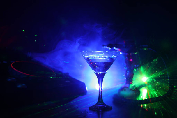 Glas met martini met olijfolie binnen op dj-controller in nachtclub. DJ Console met club drankje op muziek feest in nachtclub met stijlvolle Oosterse shisha - Foto, afbeelding