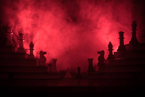 Иерархия бизнеса. Стратегическая концепция шахматных фигур. Шахматы, стоящие на пирамиде книг с королем на вершине. Темный туманный фон с тонированным светом. Копирование пространства
. - Фото, изображение