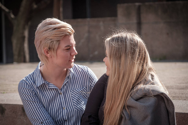 duas lésbicas gays mulheres em seus vinte anos se apoiam em uma paisagem da cidade na Cidade do Cabo, África do Sul
 - Foto, Imagem