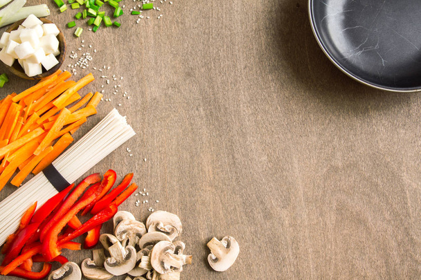 Vegetarian vegan asian food ingredients for stir fry with tofu, noodles, mushrooms and vegetables over wooden background with copy space. - Foto, Imagem