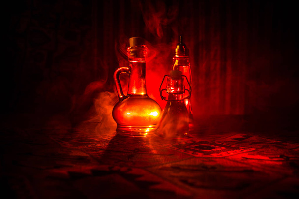 Antieke en vintage glazen flessen op donkere mistige achtergrond met licht. Vergif of magische vloeibare concept. - Foto, afbeelding
