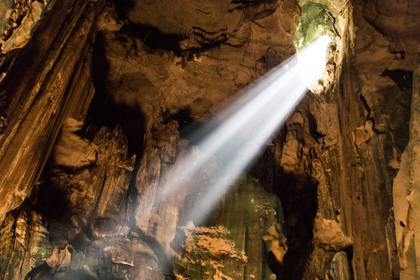 Shafts of sunlight stream down from large holes in the cave roof to illuminate the chamber in Mulu National Park, Sarawak - Photo, Image