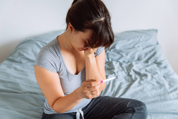 jeune jolie femme tenant test de grossesse avec vue malheureuse
 - Photo, image