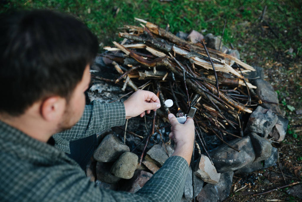 若い男は、調理の火を構築します。キャンプのコンセプト - 写真・画像