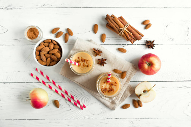 Apple pie protein smoothie drink with almond milk. Homemade apple smoothie with apple pie spices (cinnamon) on white wooden background, copy space. - 写真・画像
