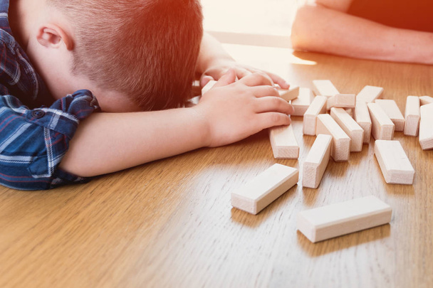 Kid lost the jenga game. His tower from wooden blocks had fallen. Concept of risk and strategy in business and construction. - Fotoğraf, Görsel