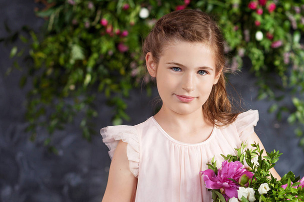 Portrait of the lovely little girl with a bouquet of flowers. Looking at camera - Photo, image