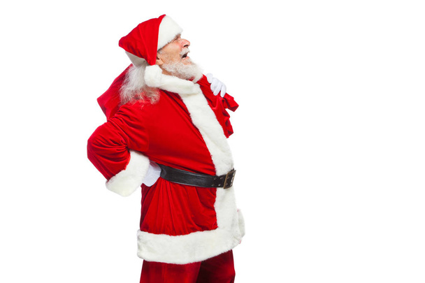 クリスマス。サンタ クロースは、背中の痛みに苦しんでいるし、彼の背中に赤いバッグの贈り物を保持しています。白い背景に分離. - 写真・画像
