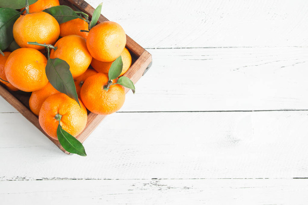 Mandarinas (naranjas, clementinas, cítricos) con hojas verdes sobre fondo de madera blanca con espacio para copiar
 - Foto, Imagen