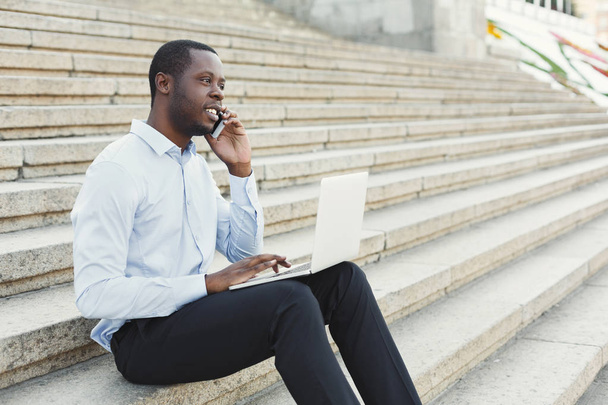 Empresário feliz afro-americano trabalhando com laptop ao ar livre
 - Foto, Imagem