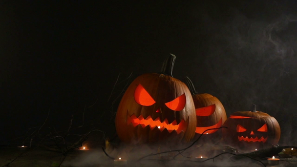 Halloween sütőtök fej jack o lámpák és gyertyák ködben - Felvétel, videó