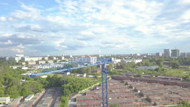 Luchtfoto video van een verhoogde bouw kraan tegen de blauwe lucht en de witte wolken op een zomerdag op het bouwterrein verhoogt de lading. - Video