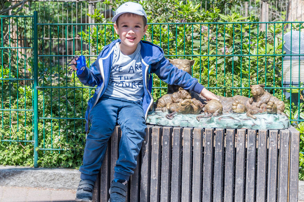 HELSINKI, FINLAND - JUNE 18, 2018: Young boy sitting near wooden tigers sculpture at Korkeasaari Zoo in Helsinki, Finland. - Photo, Image