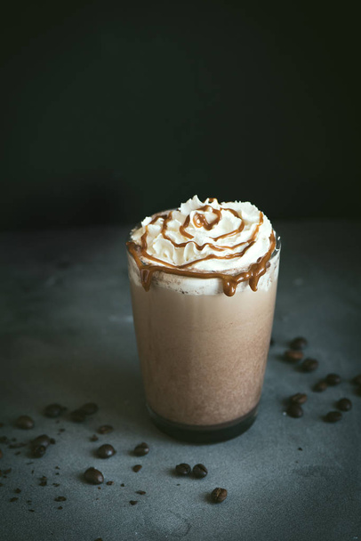 Cold Frappe Coffee (frappuccino) with whipped cream and caramel on dark background, copy space. - Фото, изображение