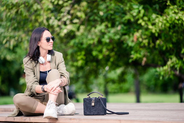 公園に座っている間、かわいい女性は携帯電話でテキストメッセージを読んでいます. - 写真・画像