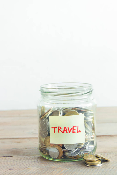 Coins in glass jar with red heart and Travel label. Money savings, plans and dreams concept, copy space. - Valokuva, kuva
