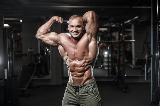 Handsome strong bodybuilder athletic man pumping up muscles workout bodybuilding concept background - muscular bodybuilder handsome men doing exercises in gym naked torso sport and diet concept - Foto, immagini