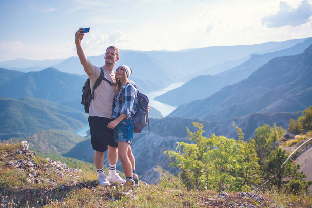 Breathing the fresh mountain air. Young couple making selfie while hiking in the mountain in the summer. Hiking concept in the mountain in summer - Foto, immagini