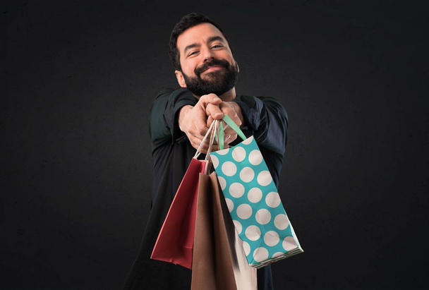 Handsome man with beard with shopping bag on black background - Foto, Imagen