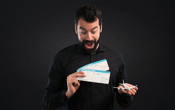 Handsome man with beard holding air tickets on black background - Photo, Image