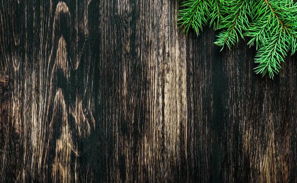 Spruce branches on a dark vintage wooden background. Christmas concept - Foto, imagen