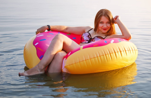 Boldog, fiatal lány, porcukros fánk úszó és mosolyogva a tengerbe nyári idő. - Fotó, kép