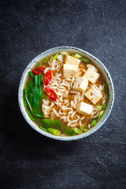 Japanese ramen soup with tofu on dark stone background. Miso soup with ramen noodles and tofu in ceramic bowl, asian traditional food. - Valokuva, kuva