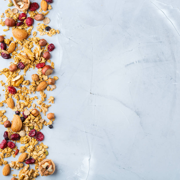 Food and drink, dieting, nutrition breakfast concept. Healthy homemade cereal granola muesli with oats, nuts, dry berries on a cozy kitchen table. Top view flat lay copy space background - Photo, image