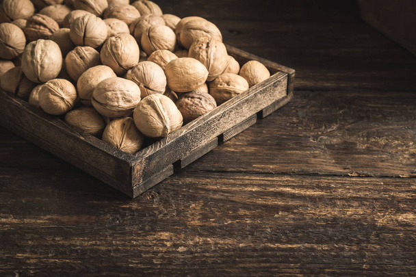 Organic Walnuts in rustic wooden box, top view, copy space. Seasonal harvest of walnuts. - Fotografie, Obrázek