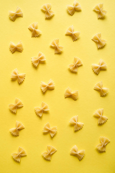Farfalle Pasta on yellow background, top view, flat lay. - Фото, зображення