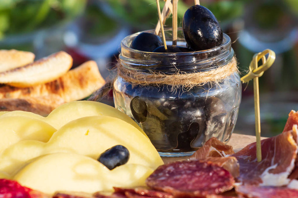 Käseteller serviert mit Trauben, Marmelade, Feigen, Crackern und Nüssen auf einem hölzernen Hintergrund - Foto, Bild