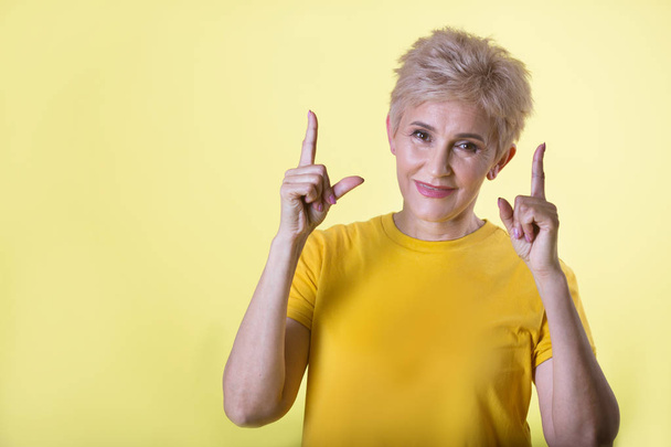 beautiful stylish woman with a short hairstyle on a yellow background - Zdjęcie, obraz
