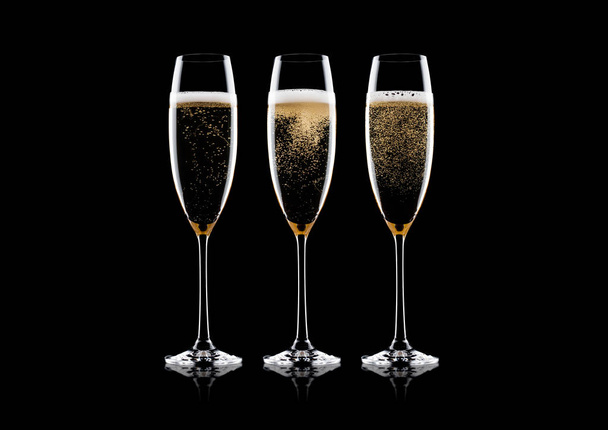 Elegantes copas de champán amarillo con burbujas sobre fondo negro con reflejo
 - Foto, Imagen