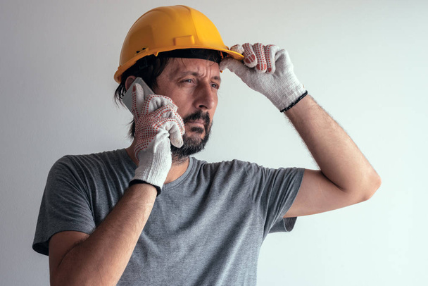 Construction engineer talking on mobile phone, serious adult male person using smartphone for communication with workers on building site - Foto, Imagem