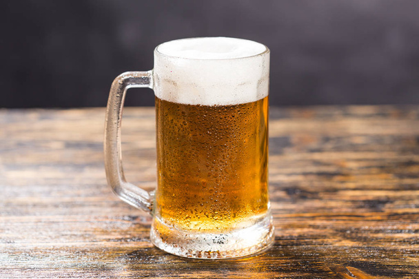 Bicchiere freddo di birra lager con schiuma e rugiada sul tavolo di legno
 - Foto, immagini