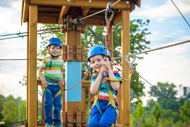 Crianças felizes se divertindo no parque de aventura. Dois meninos pré-escolares saudáveis aventureiros, irmãos gêmeos desfrutando de um dia ativo ao ar livre subindo nas árvores. Conceito de amizade e fraternidade
. - Foto, Imagem
