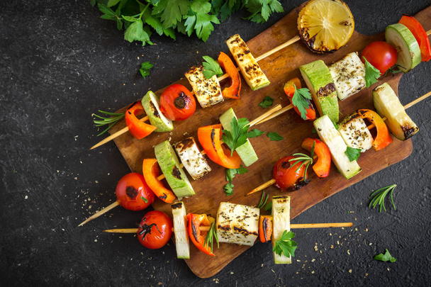 Vegetarian grilling. Vegetarian skewers with halloumi cheese and vegetables on black background, copy space. - Fotó, kép