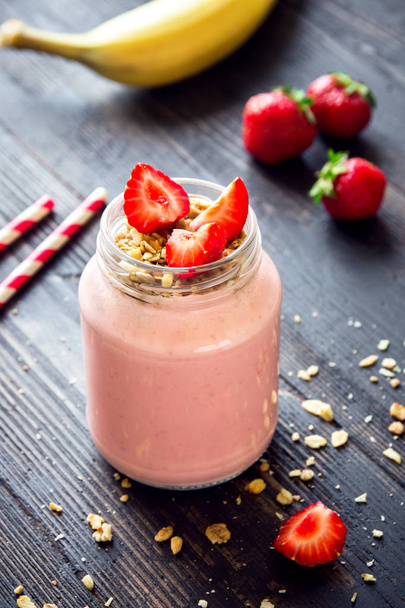 Strawberry and banana smoothie with homemade granola. Healthy breakfast or snack. Banana and strawberry smoothie in glass jar. - Photo, image