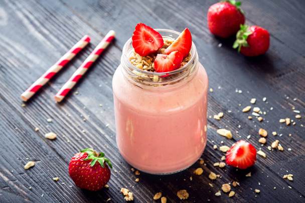 Strawberry smoothie with homemade granola. Healthy breakfast or snack. Banana and strawberry smoothie in glass jar. - Photo, image