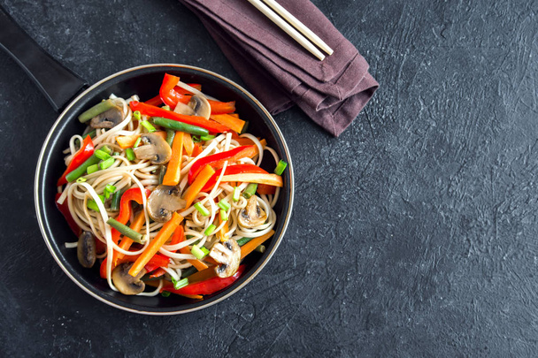 Stir fry with udon noodles, mushrooms and vegetables. Asian vegan vegetarian food, meal, stir fry over black background, copy space. - Fotó, kép